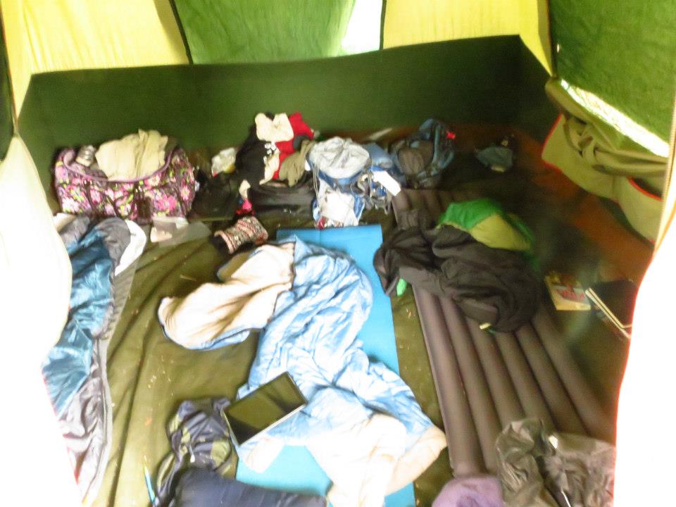 a mess of sleeping pads, sleeping bags, clothes and other gear strewn about a tent
